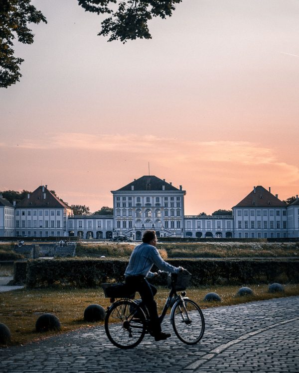 ein Radfahrer vor dem Nymphenburger Schloss im Sonnenuntergang.